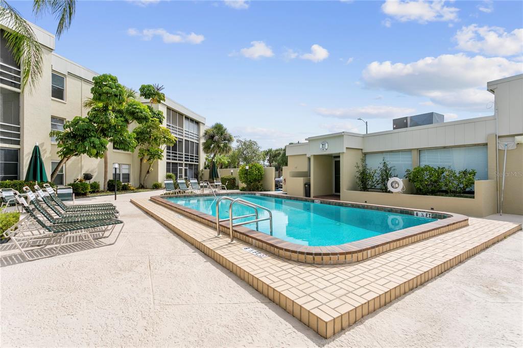 An outdoor swimming pool is surrounded by a paved deck and multi-story residential buildings — 2302 S MANHATTAN AVENUE UNIT 111, TAMPA, FL