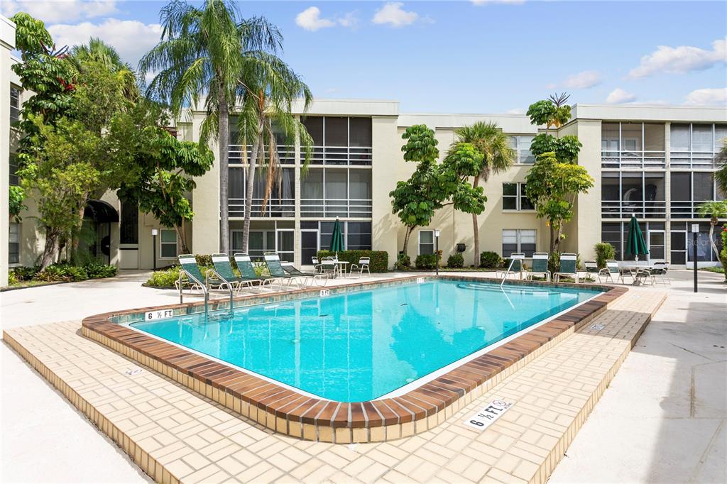 A rectangular swimming pool sits in a courtyard surrounded by a multi-story apartment building — 2302 S MANHATTAN AVENUE UNIT 111, TAMPA, FL