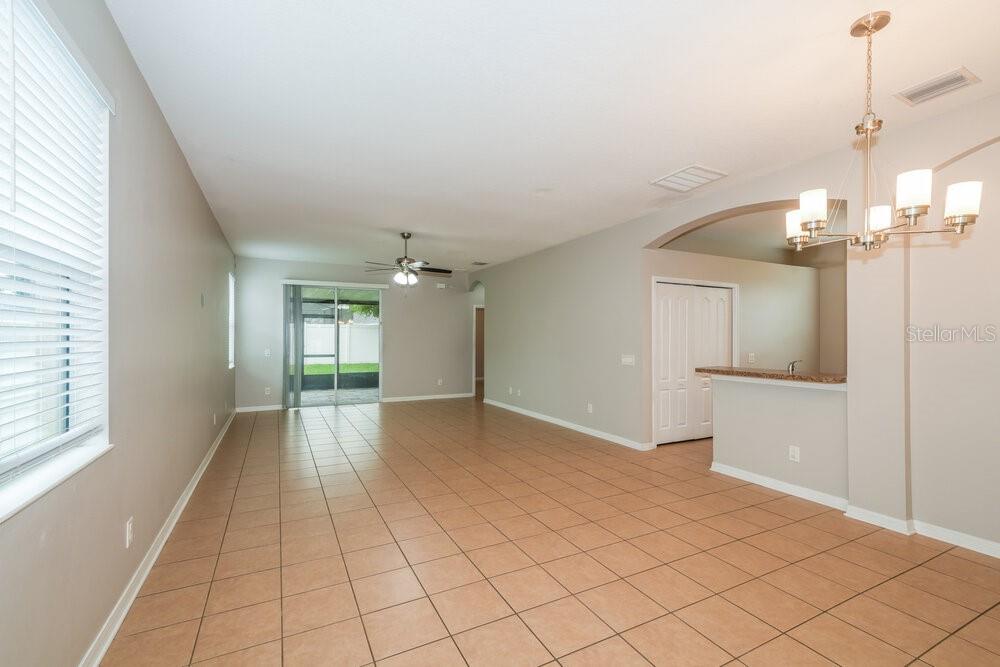 An open-concept living and dining area features beige tile flooring and a chandelier — 8226 SUMMER WOOD LANE, RIVERVIEW, FL