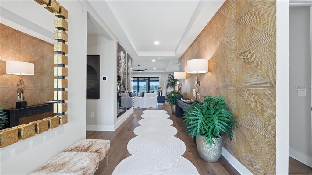 A hallway features wood-paneled walls, a scalloped runner rug, and a large gold-framed mirror — 12866 PINNACLE LANE, VENICE, FL
