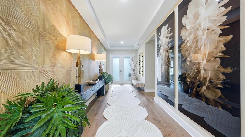 A bright entryway features a textured wall, a long console table, and a patterned rug — 12866 PINNACLE LANE, VENICE, FL