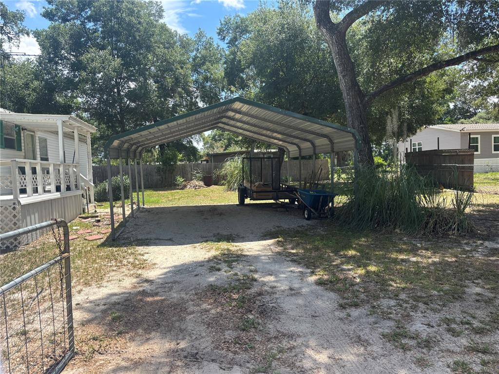 A metal carport stands on a sandy lot next to a mobile home — 2695 NE 147TH COURT, SILVER SPRINGS, FL