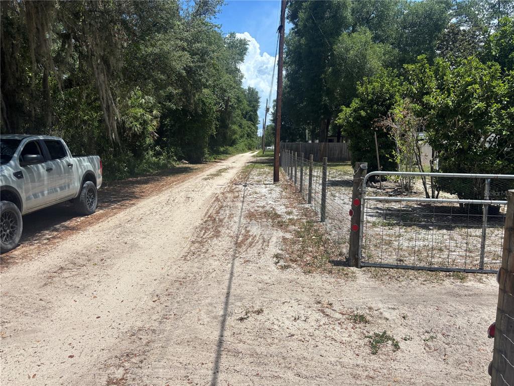 A dirt road runs alongside a wire fence and a parked pickup truck — 2695 NE 147TH COURT, SILVER SPRINGS, FL