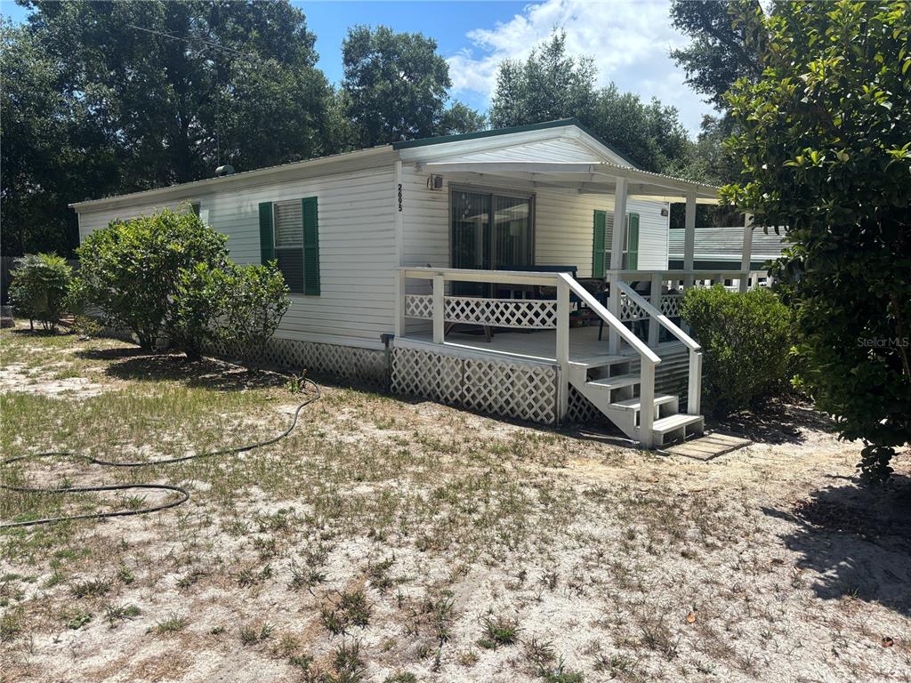A white mobile home features a wooden deck with lattice skirting and green shutters — 2695 NE 147TH COURT, SILVER SPRINGS, FL