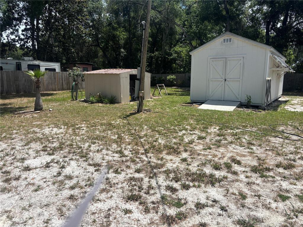 A backyard features a white shed, a smaller metal storage unit, and a palm tree — 2695 NE 147TH COURT, SILVER SPRINGS, FL