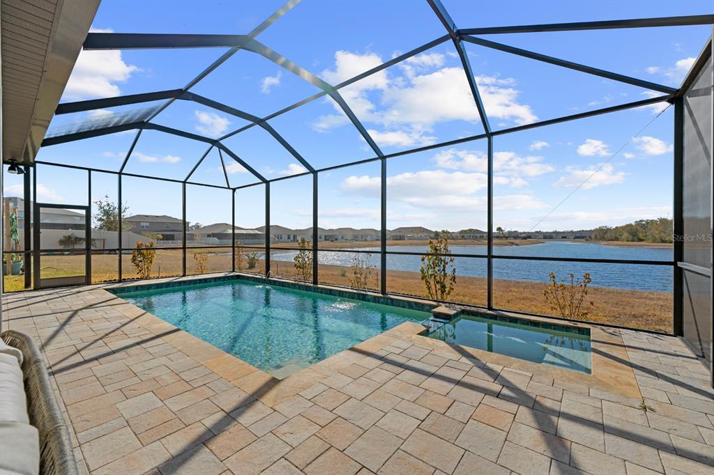 A screened-in patio features a rectangular swimming pool, a small spa, and paver decking — 13060 WILLOW GROVE DRIVE, RIVERVIEW, FL