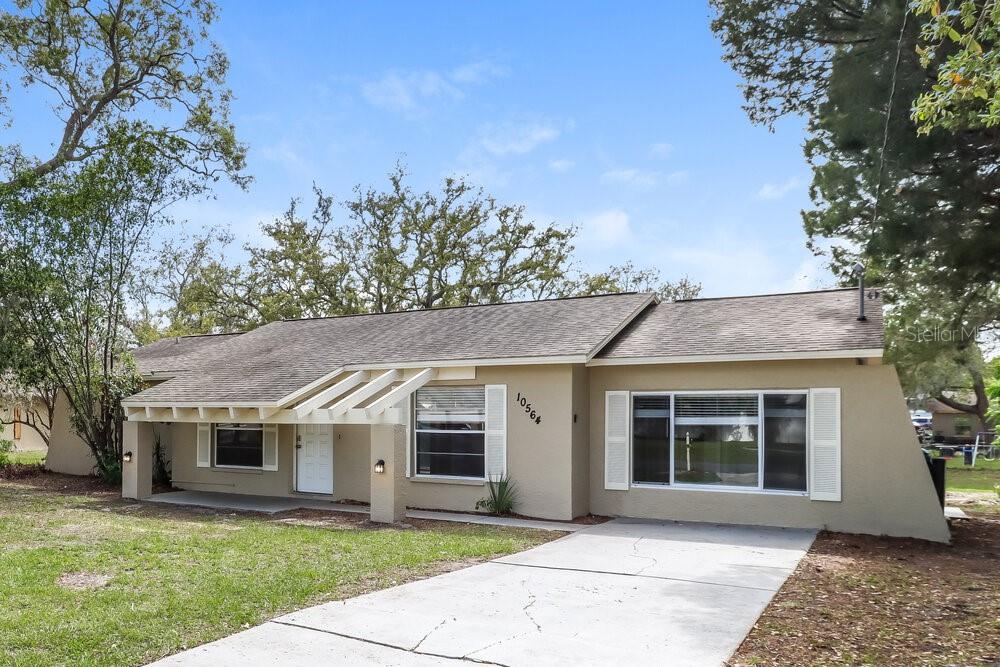 A single-story house with a beige exterior, a concrete driveway, and a covered front porch — 10564 BLYTHVILLE ROAD, SPRING HILL, FL