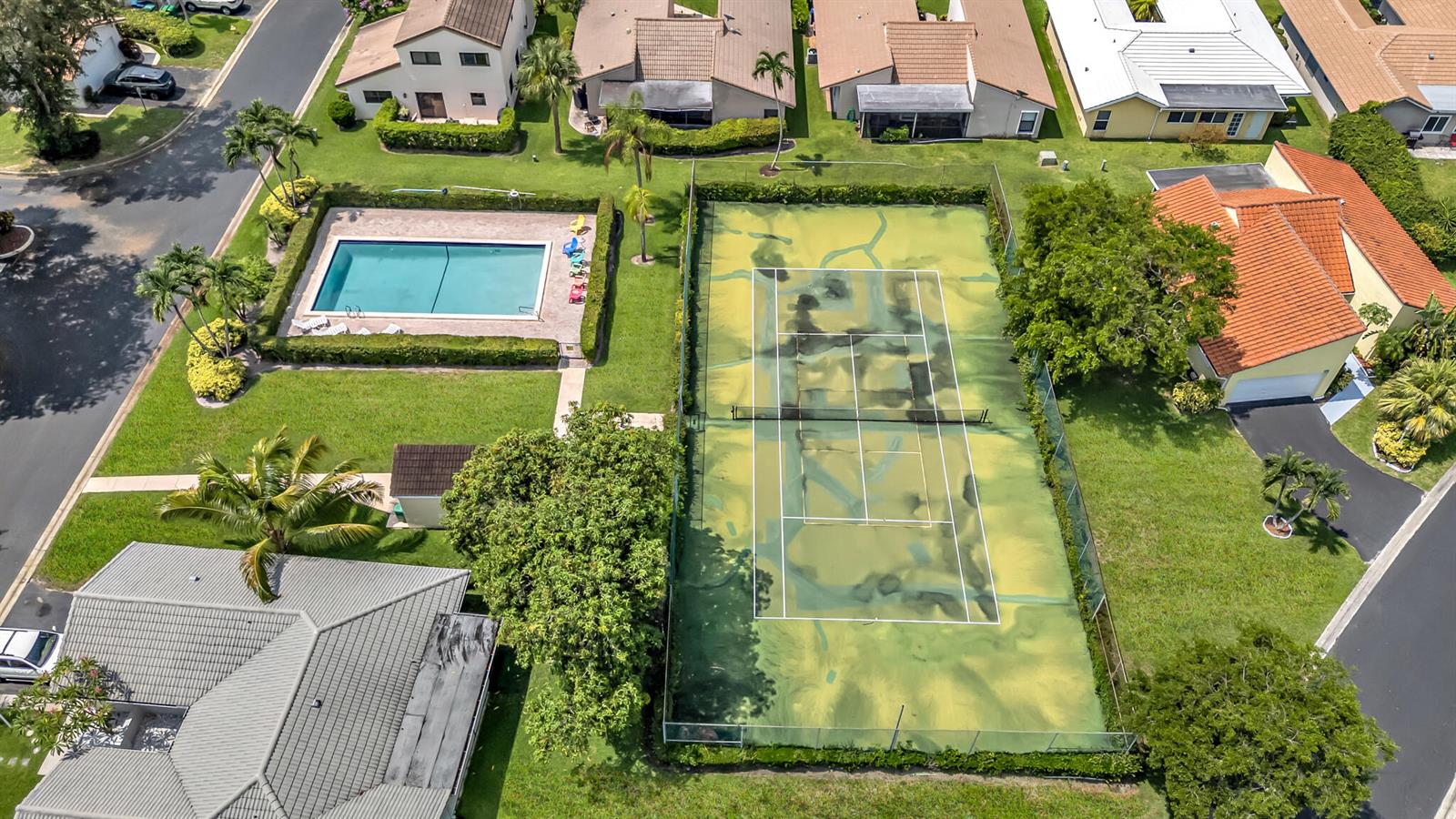 An aerial view shows a residential property with a swimming pool and a weathered tennis court — 1273 Spring Circle Drive, Coral Springs FL 33071, CORAL SPRINGS, FL
