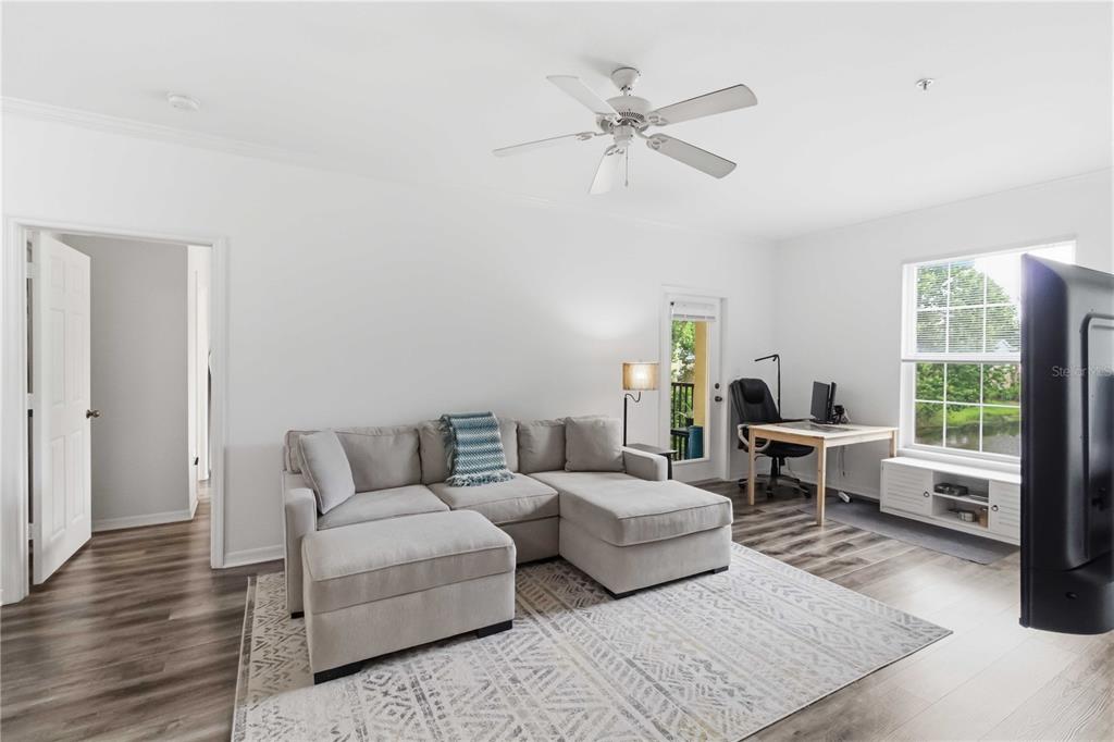 A living room features a gray sectional sofa, a desk, and a large window — 10201 COURTNEY PALMS BOULEVARD UNIT 204, TAMPA, FL