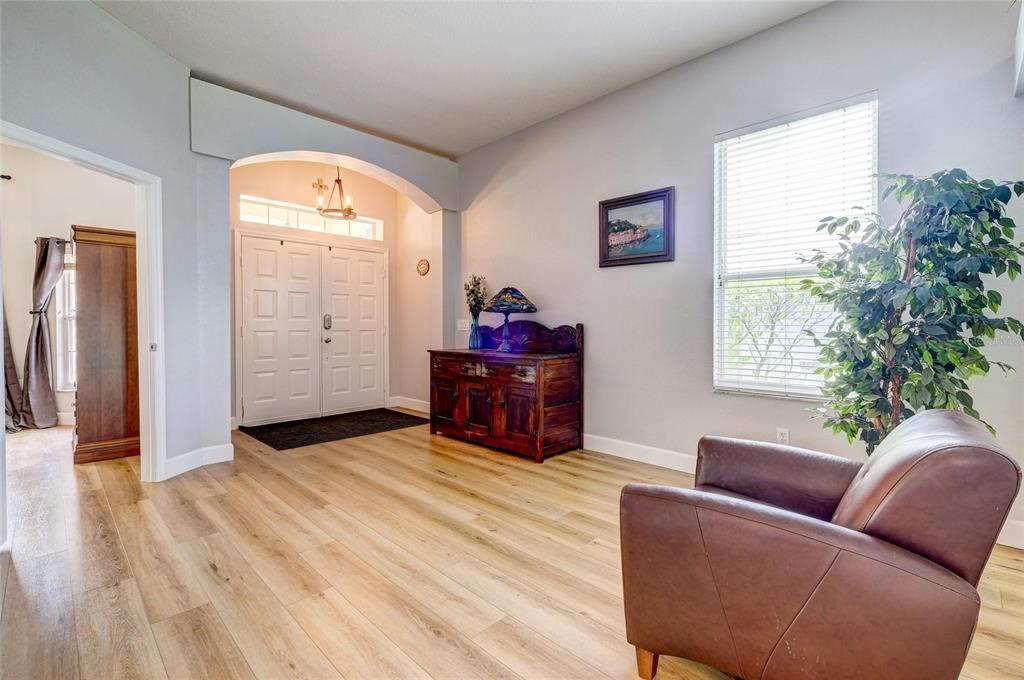 A foyer with light wood flooring, a dark wood cabinet, and a brown leather armchair — 6462 GOLDEN LEAF COURT, LAKEWOOD RANCH, FL