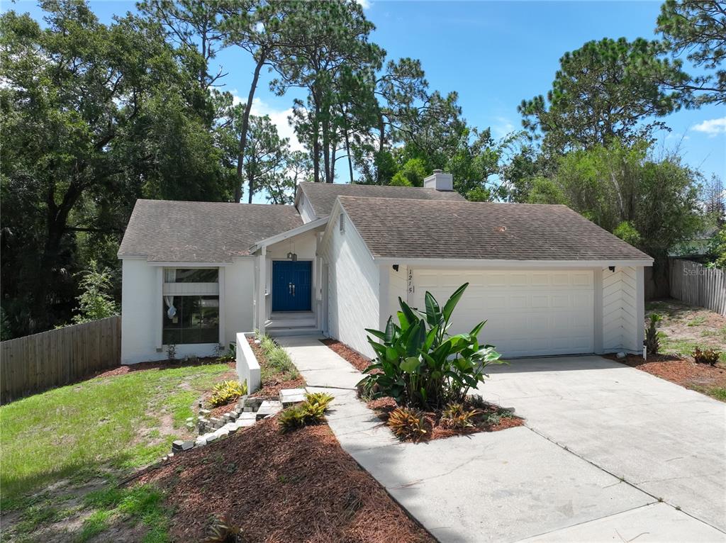 A single-story white house features a blue front door, a two-car garage, and landscaping — 1215 DUNCAN COURT, LONGWOOD, FL