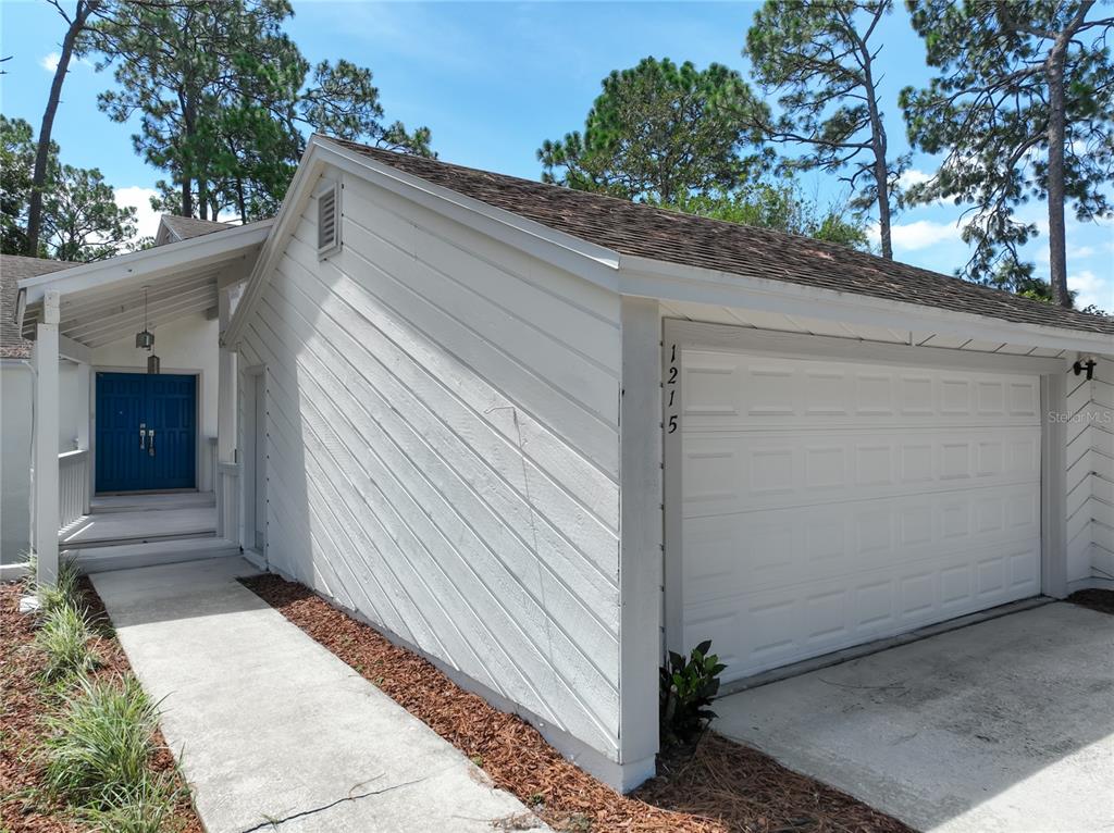 A white house exterior features a garage, a blue front door, and a concrete walkway — 1215 DUNCAN COURT, LONGWOOD, FL