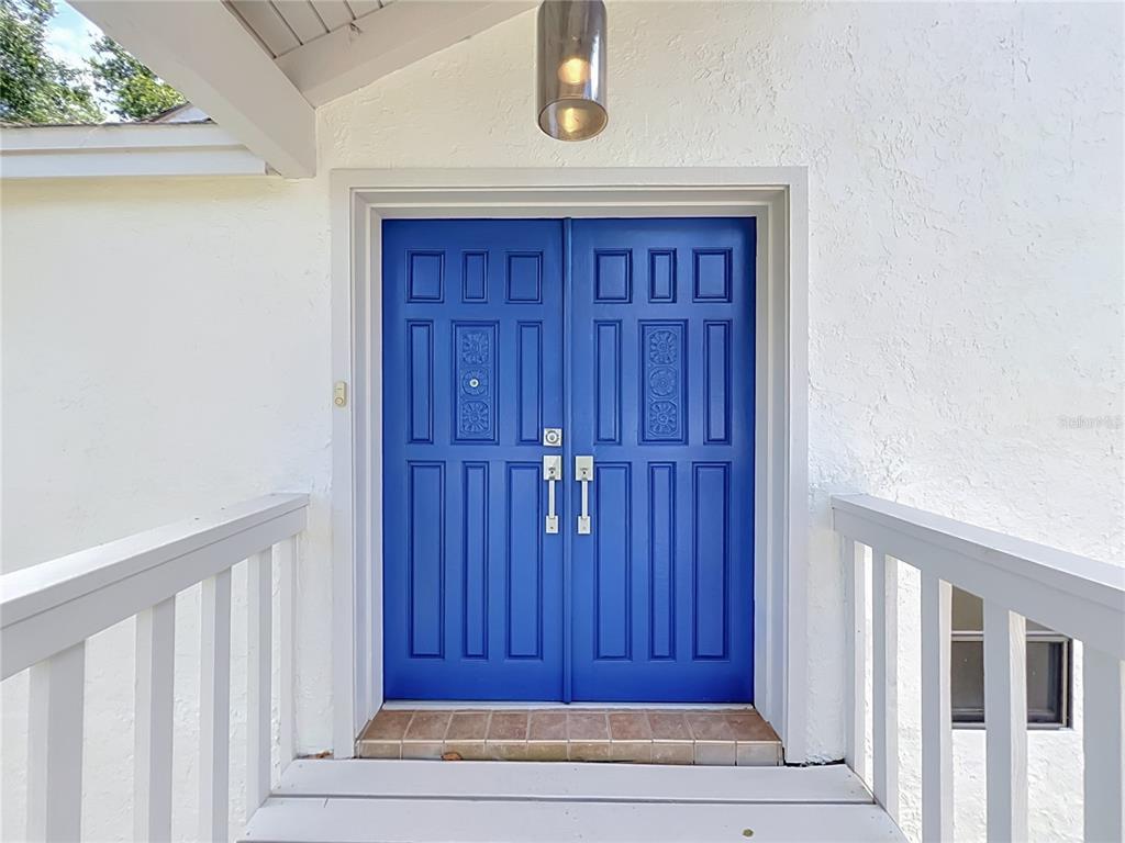 A bright blue double front door with decorative panels is set in a white wall — 1215 DUNCAN COURT, LONGWOOD, FL