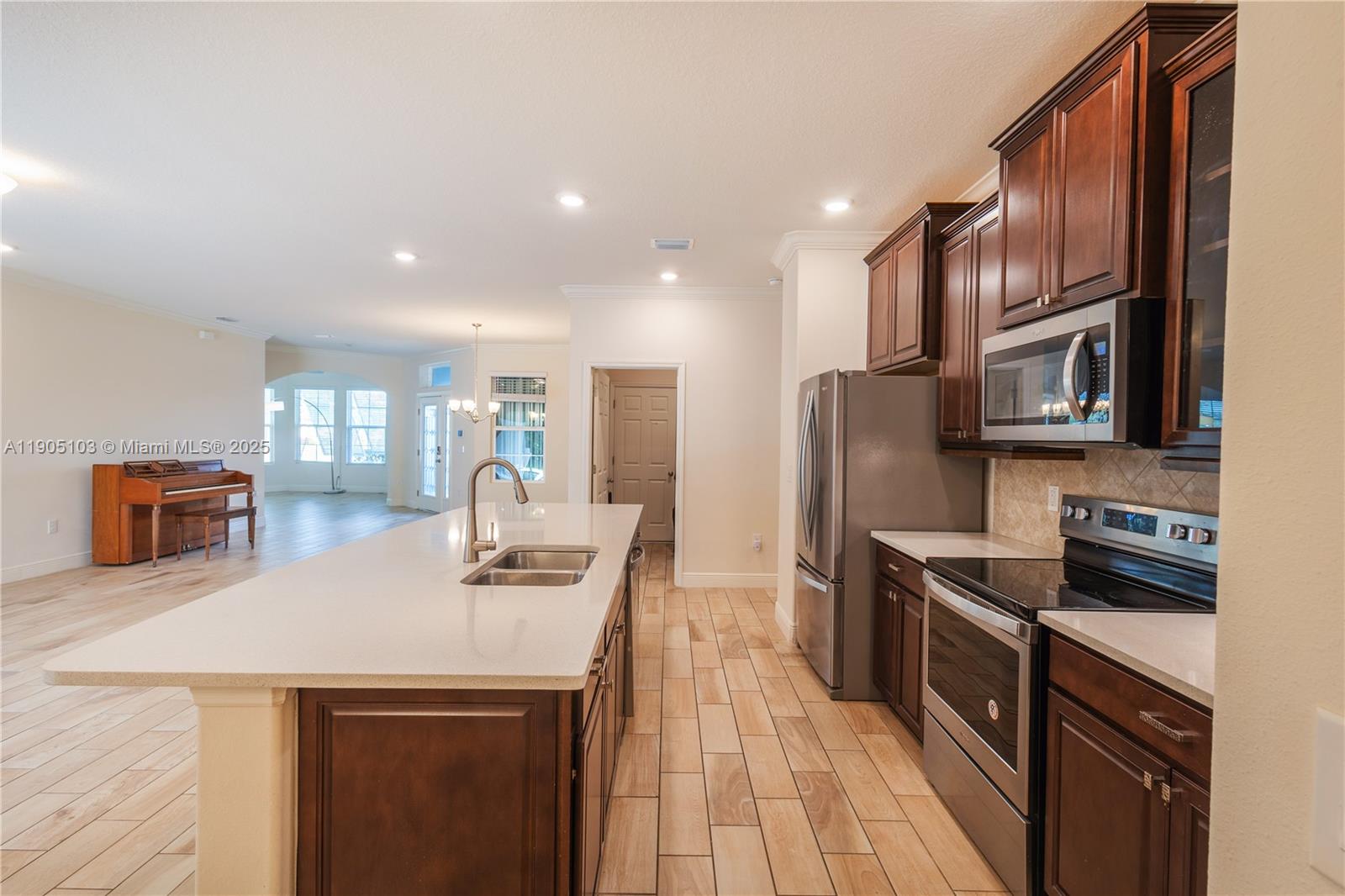 A kitchen features dark wood cabinets, stainless steel appliances, and a large white island — 2547 Saint Lucia Cir, Vero Beach FL 32967, VERO BEACH, FL