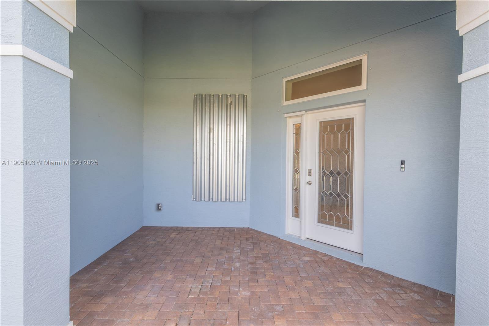 A covered entryway features light blue walls, a brick paver floor, and a white door — 2547 Saint Lucia Cir, Vero Beach FL 32967, VERO BEACH, FL