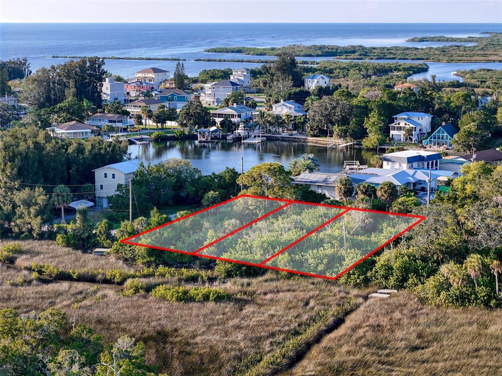 An aerial view shows a rectangular, tree-covered lot outlined in red near a coastal waterway — lot 10 NOWIKI AVENUE, HUDSON, FL