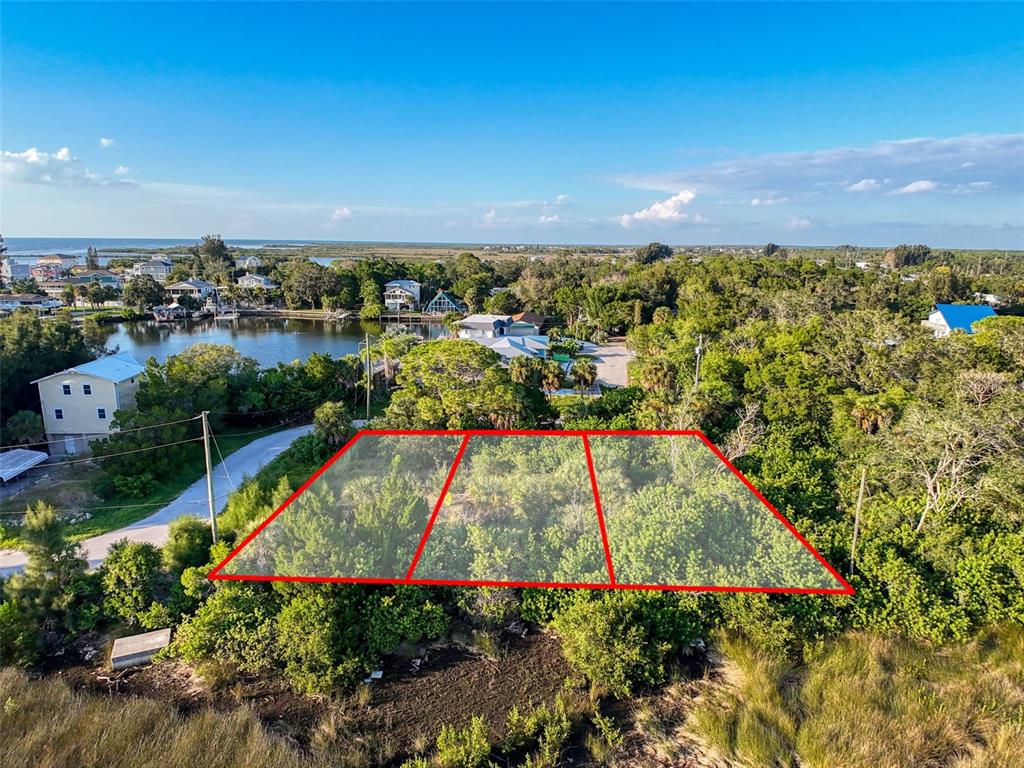 An aerial view shows a rectangular, tree-covered lot outlined in red near a coastal waterway — lot 10 NOWIKI AVENUE, HUDSON, FL