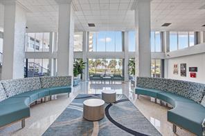 A bright lobby features two curved teal sofas, circular tables, and large floor-to-ceiling windows — 405 N Ocean Boulevard # 1918, Pompano Beach FL 33062, POMPANO BEACH, FL
