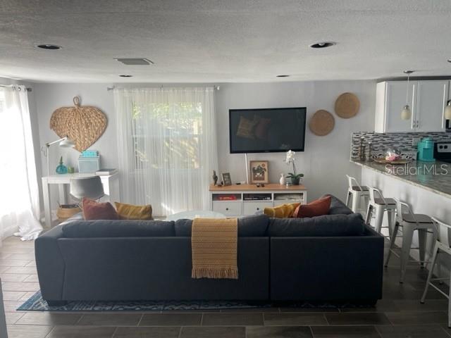 A living room features a large gray sectional sofa, a television, and a kitchen breakfast bar — 2765 61ST AVENUE N, ST PETERSBURG, FL