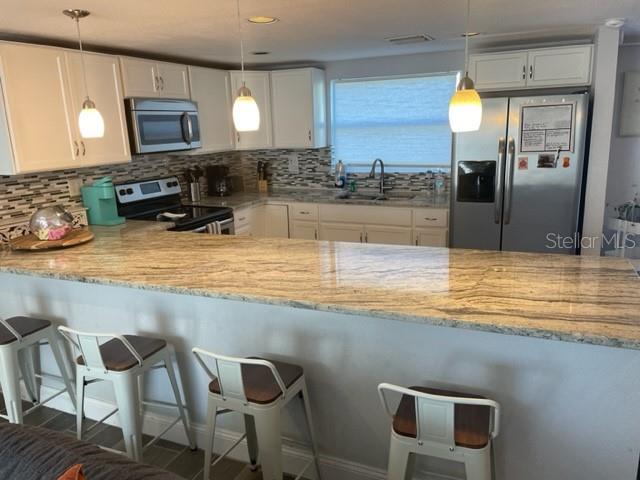 A kitchen features white cabinets, granite countertops, stainless steel appliances, and a breakfast bar — 2765 61ST AVENUE N, ST PETERSBURG, FL