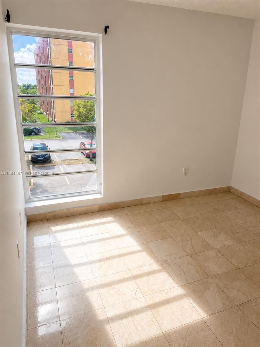 A room with beige tile flooring and a large window overlooking a parking lot — 4721 NW 7th St # 12, Miami FL 33126, MIAMI, FL