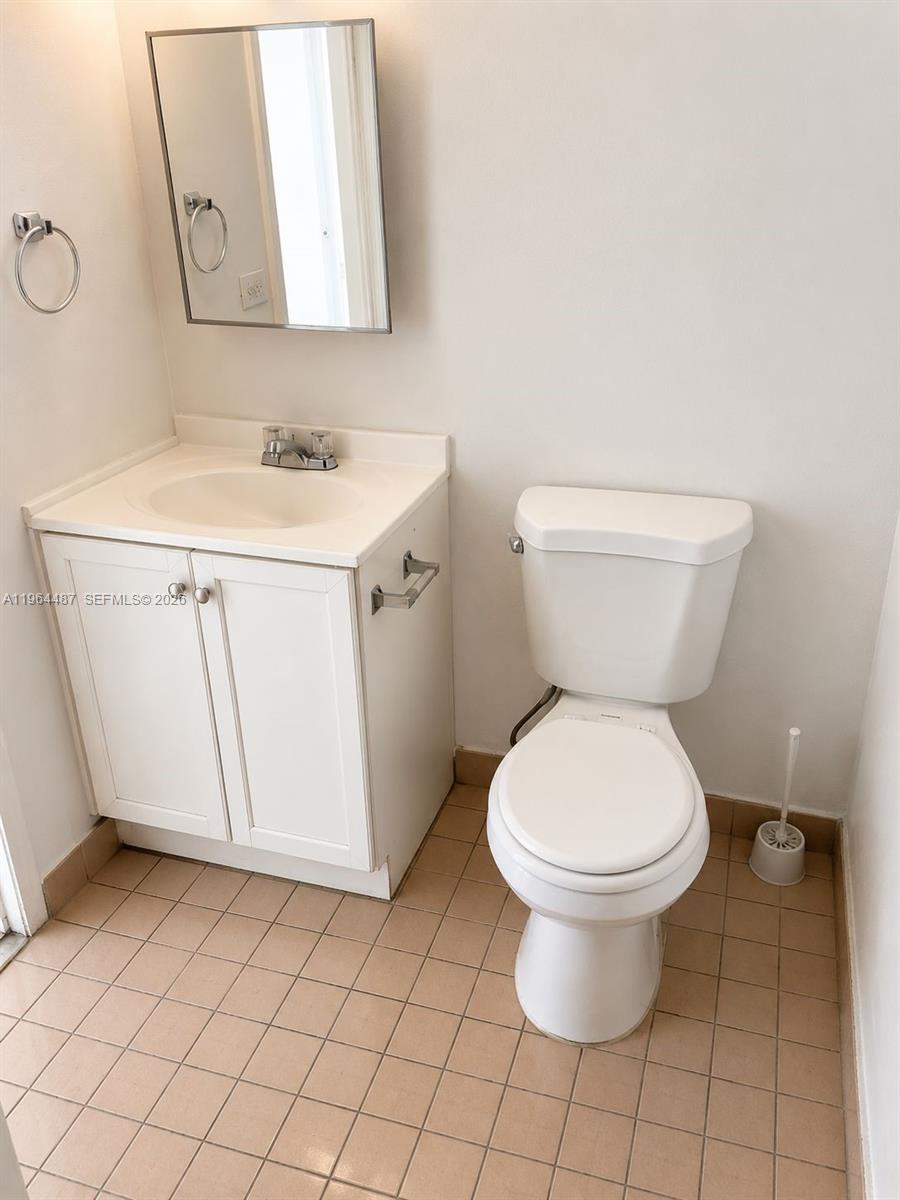 A small bathroom features a white vanity, a mirror, and a white toilet on tile flooring — 4721 NW 7th St # 12, Miami FL 33126, MIAMI, FL