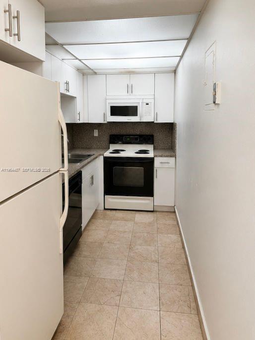 A galley-style kitchen features white cabinets, a black stove, and light-colored tile flooring — 4721 NW 7th St # 12, Miami FL 33126, MIAMI, FL