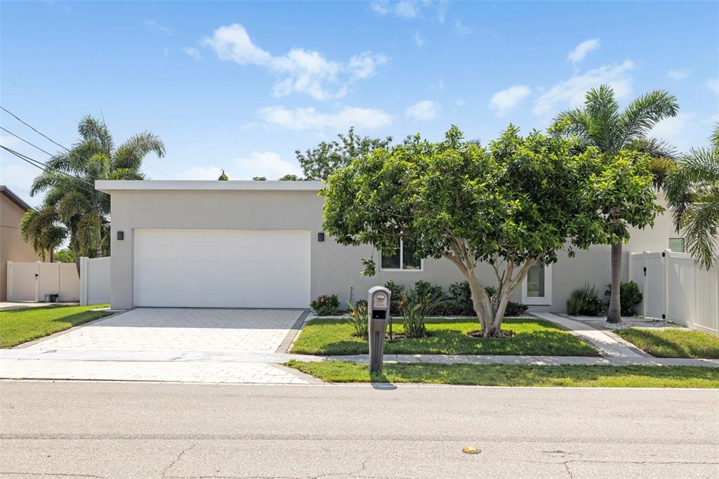 A single-story house with a white garage door, a paved driveway, and a large tree — 4524 RIVERWOOD AVENUE, SARASOTA, FL