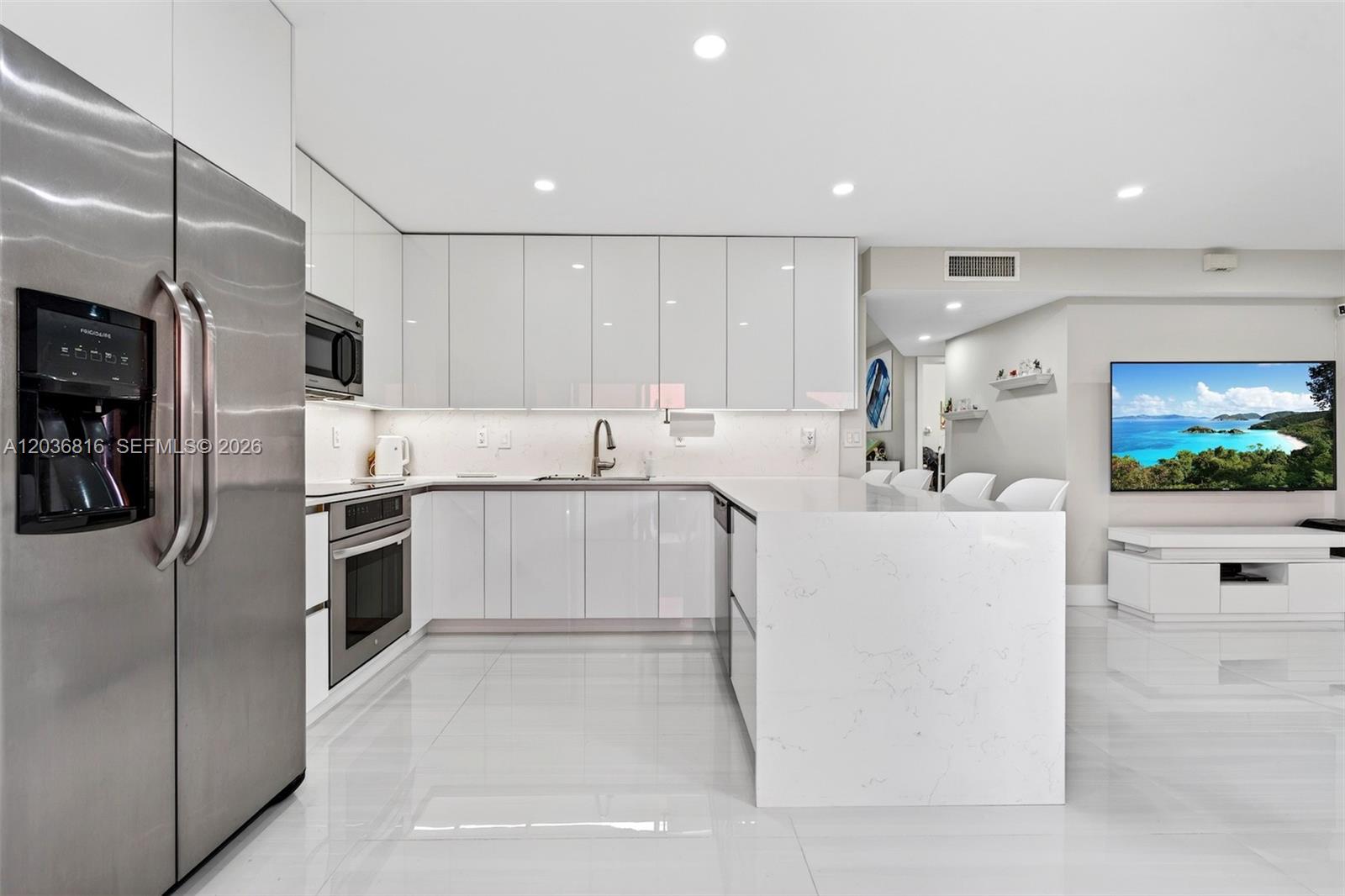 A modern kitchen features white glossy cabinets, marble-patterned countertops, and stainless steel appliances — 11115 W Okeechobee Rd # 123, Hialeah Gardens FL 33018, HIALEAH GARDENS, FL