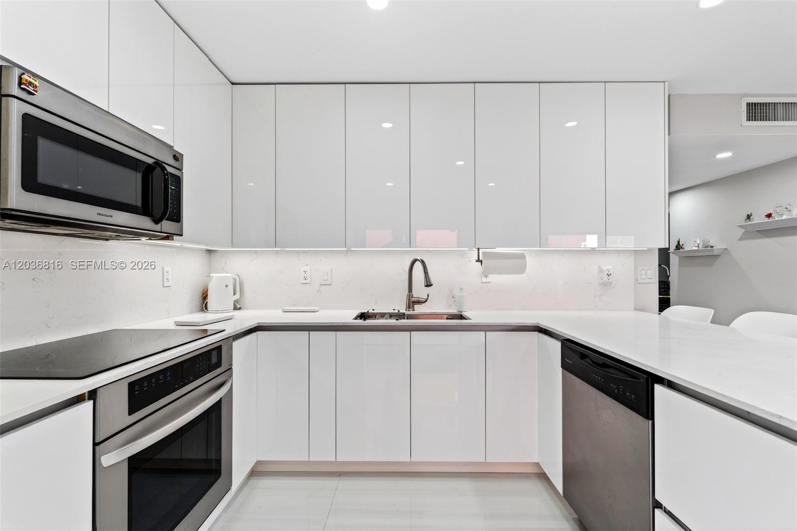 A modern kitchen features white high-gloss cabinets, stainless steel appliances, and white quartz countertops — 11115 W Okeechobee Rd # 123, Hialeah Gardens FL 33018, HIALEAH GARDENS, FL