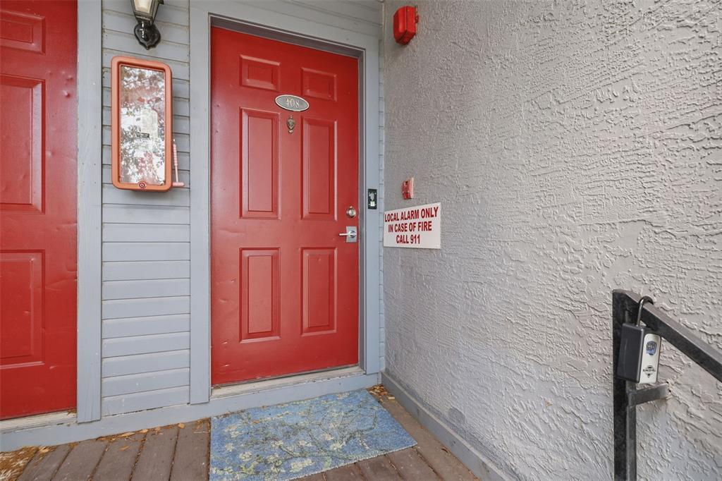 A red front door with a number plate and a fire alarm sign on the wall — 10263 GANDY BOULEVARD N UNIT 408, ST PETERSBURG, FL