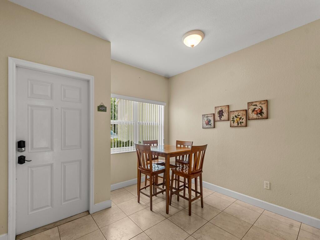 A dining area features a square wooden table with four chairs, tiled floors, and wall art — 4210 Gator Trace Avenue # B, Fort Pierce FL 34982, FORT PIERCE, FL