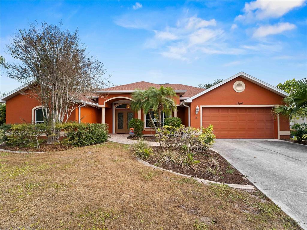 A single-story orange house with a two-car garage and a paved walkway — 1794 OKETO STREET, NORTH PORT, FL
