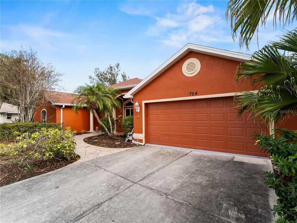 A single-story house with an orange stucco exterior and a two-car garage — 1794 OKETO STREET, NORTH PORT, FL