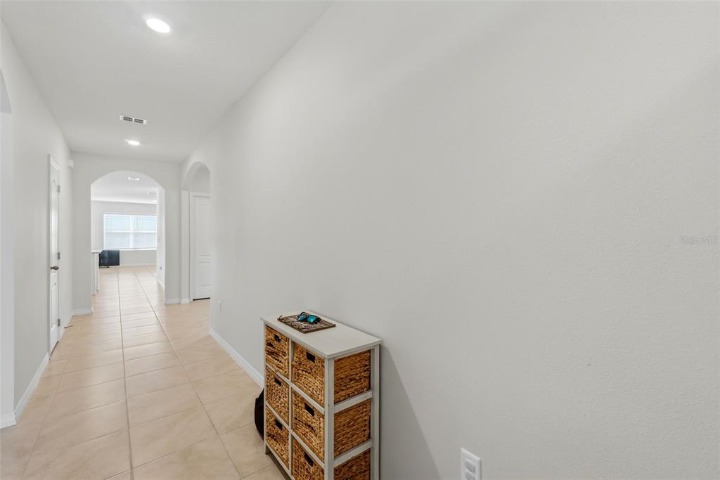 A hallway with light tile flooring leads to an open living area with a storage unit — 1349 SUGARWOOD STREET, DAVENPORT, FL