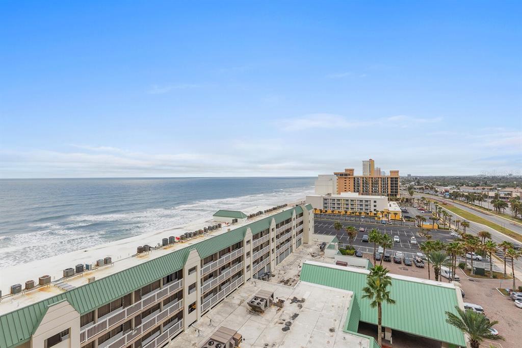 An aerial view shows a multi-story beachfront hotel with a green roof and parking lot — 2700 N ATLANTIC AVENUE UNIT 819, DAYTONA BEACH, FL