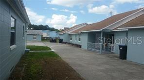A concrete driveway leads between two light blue single-story buildings under a partly cloudy sky — 2319 CARLTON DRIVE, ORLANDO, FL