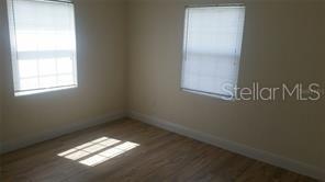 An empty bedroom with light-colored walls, wood-look flooring, and two windows with white blinds — 2319 CARLTON DRIVE, ORLANDO, FL