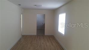 An interior room with light-colored walls, wood-look flooring, and a window on the right — 2319 CARLTON DRIVE, ORLANDO, FL