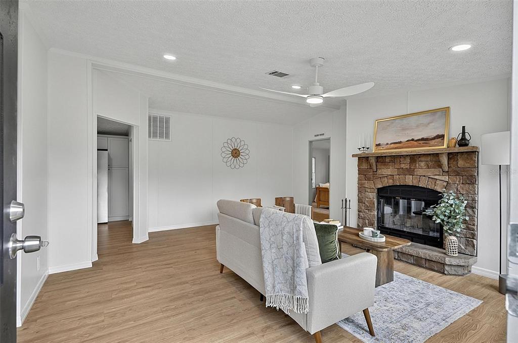 A living room features light wood floors, a stone fireplace, and a white sofa — 2318 COCONUT BOULEVARD, BUNNELL, FL