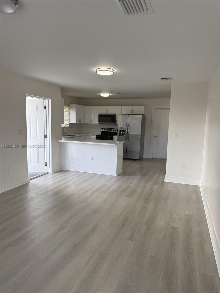 This room features a kitchen with white cabinets, stainless steel appliances, and light wood flooring — 10384 SW 173rd St # 2, Miami FL 33157, MIAMI, FL