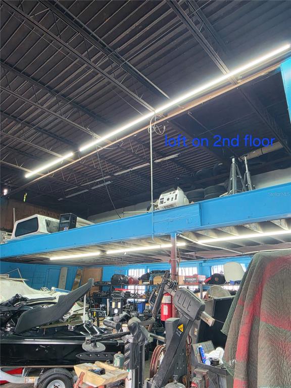 This interior view shows a workshop with a raised storage loft and exposed ceiling beams — 1942 E HILLSBOROUGH AVENUE, TAMPA, FL