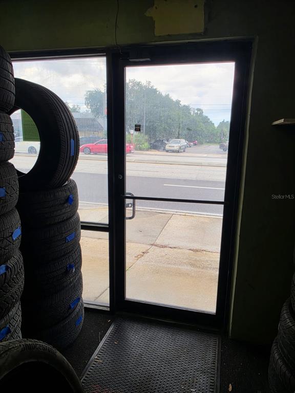 A glass door looks out from a room stacked with tires onto a street — 1942 E HILLSBOROUGH AVENUE, TAMPA, FL