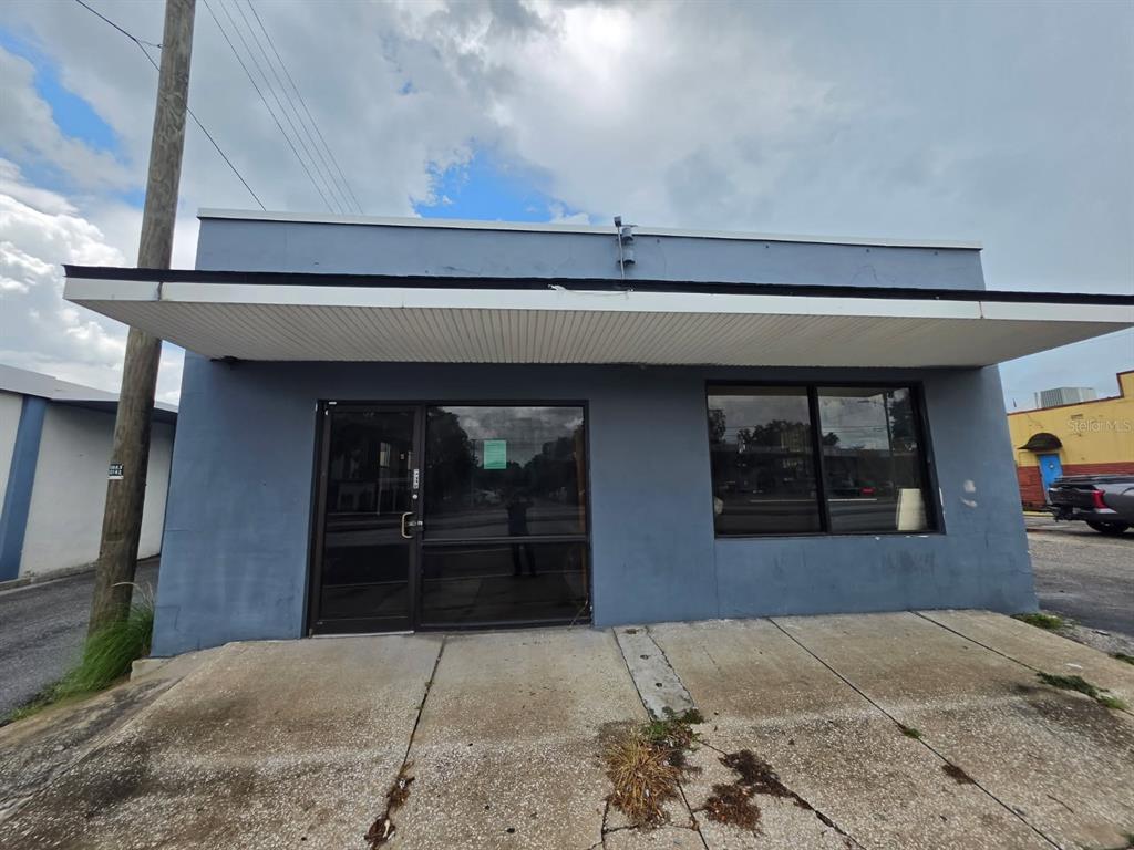 A single-story commercial building with a blue facade, a glass storefront, and a wide awning — 1942 E HILLSBOROUGH AVENUE, TAMPA, FL