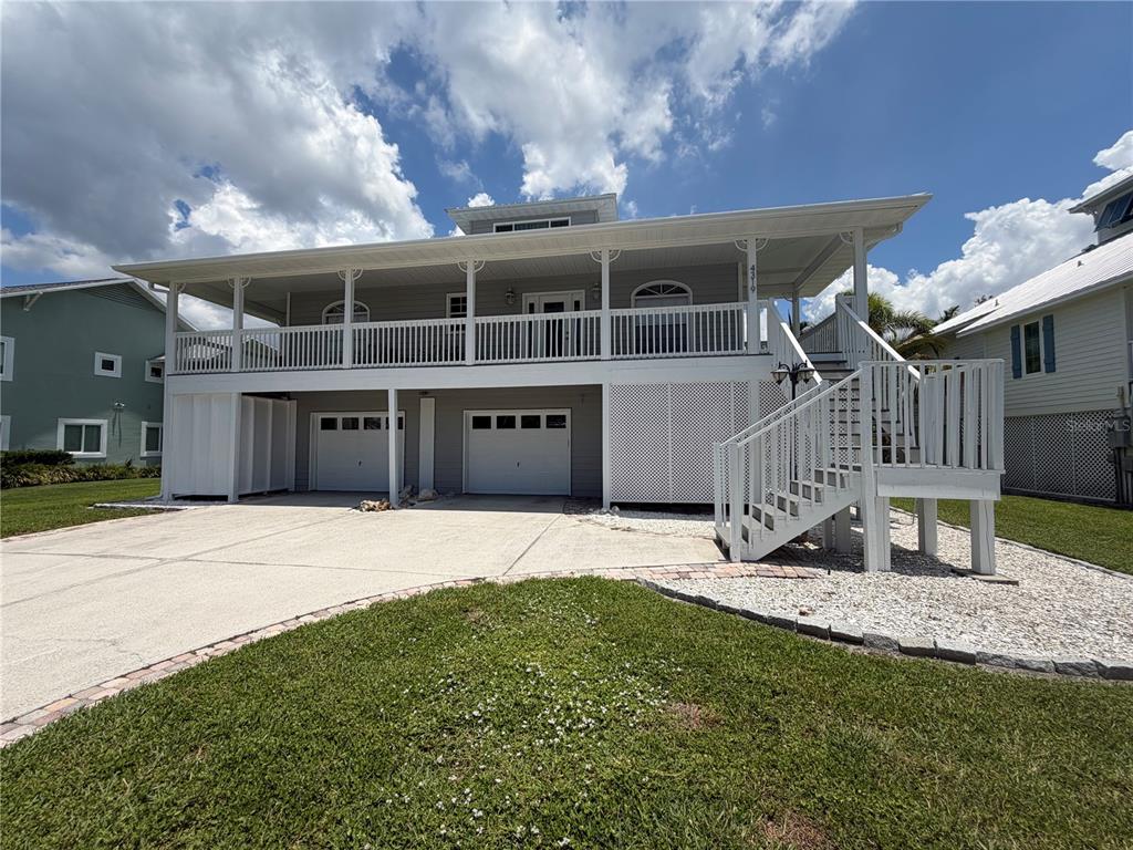 A two-story elevated house with a large front porch, two garage doors, and wooden stairs — 4319 15TH WAY, PALMETTO, FL