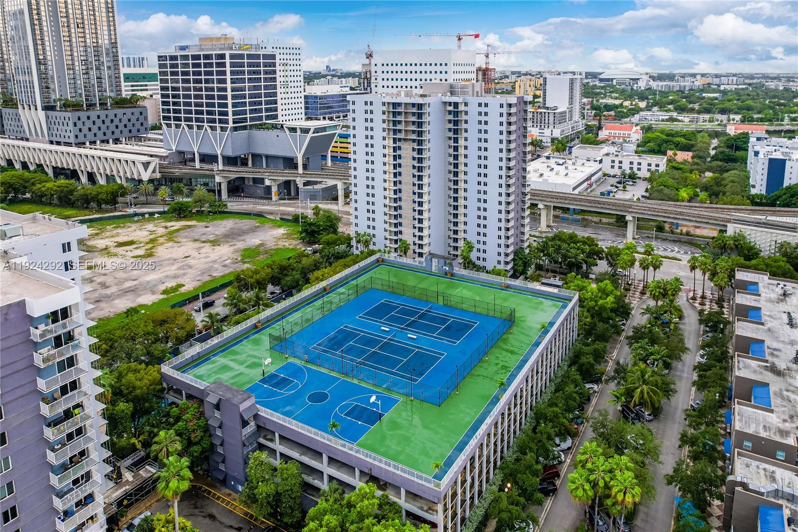 An aerial view shows a rooftop sports complex with tennis and basketball courts above parking — 850 N Miami Ave # 408, Miami FL 33136, MIAMI, FL