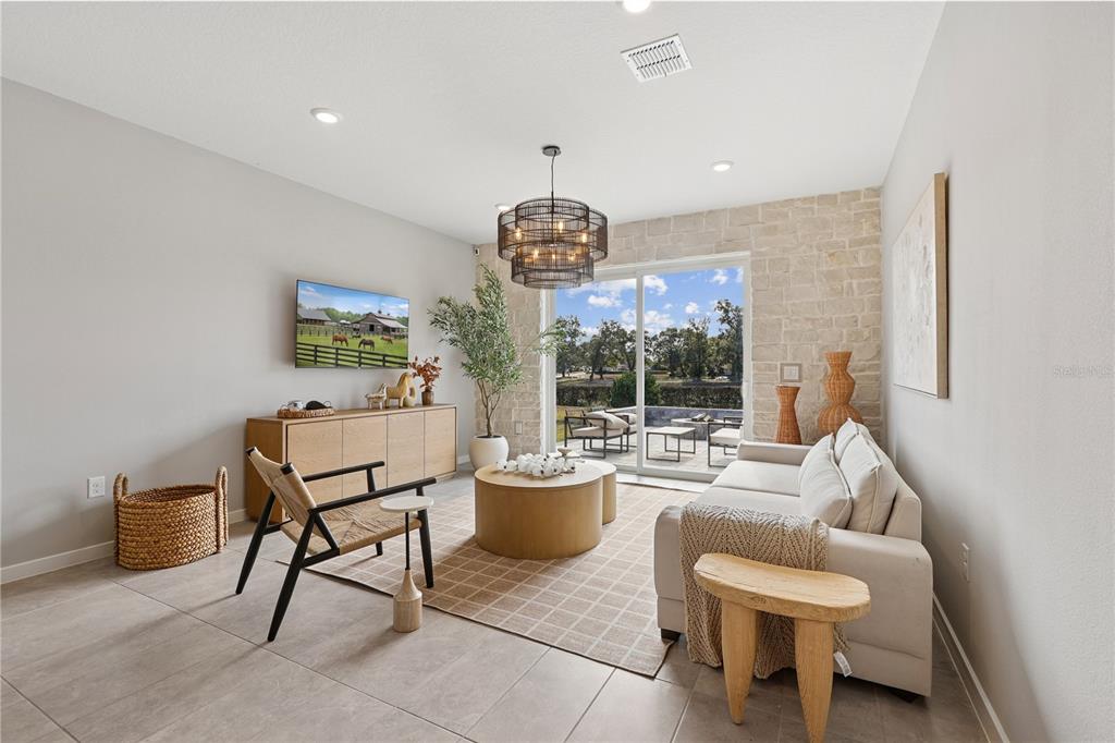 A living room features a stone accent wall, sliding glass doors, and a modern chandelier — 4474 NW 37TH STREET ROAD, OCALA, FL