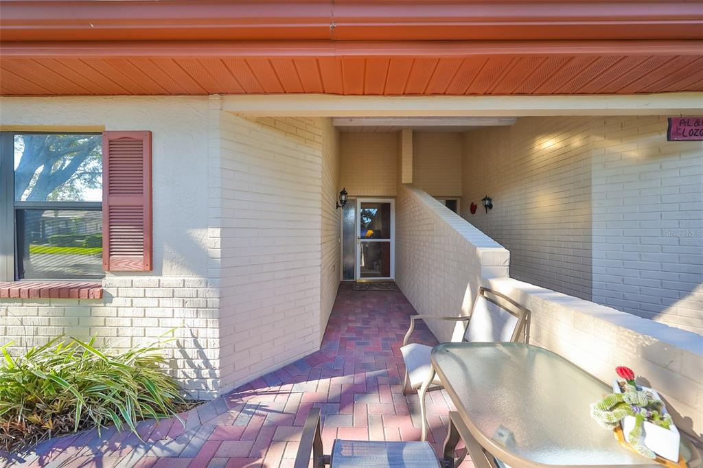 A paved patio leads to a recessed front entrance with a glass storm door — 2414 LOCKSLEY STREET, SUN CITY CENTER, FL
