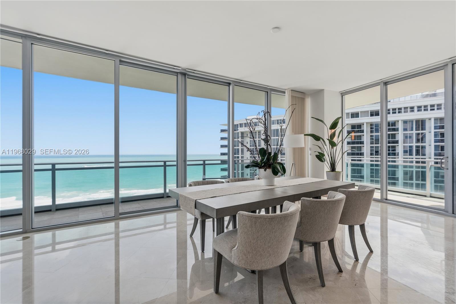 A dining room with a long table, upholstered chairs, and floor-to-ceiling windows overlooking the ocean — 10295 Collins Ave # 801, Bal Harbour FL 33154, BAL HARBOUR, FL