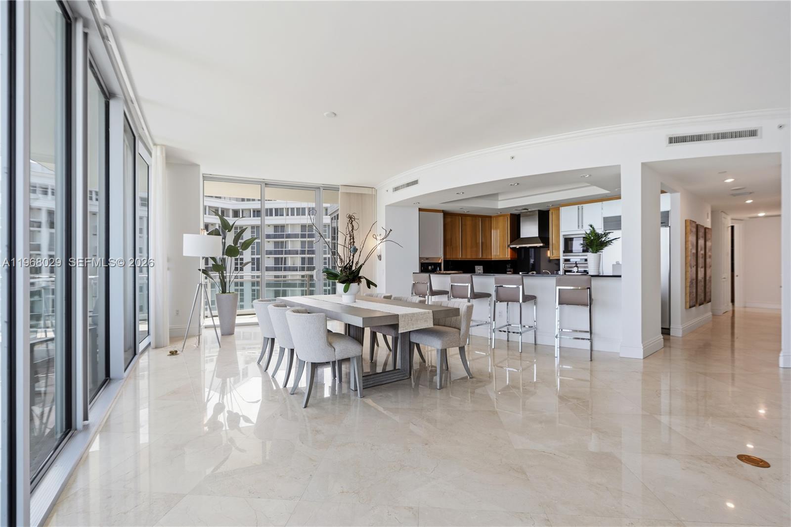 A modern dining area and kitchen feature marble floors, floor-to-ceiling windows, and neutral furnishings — 10295 Collins Ave # 801, Bal Harbour FL 33154, BAL HARBOUR, FL